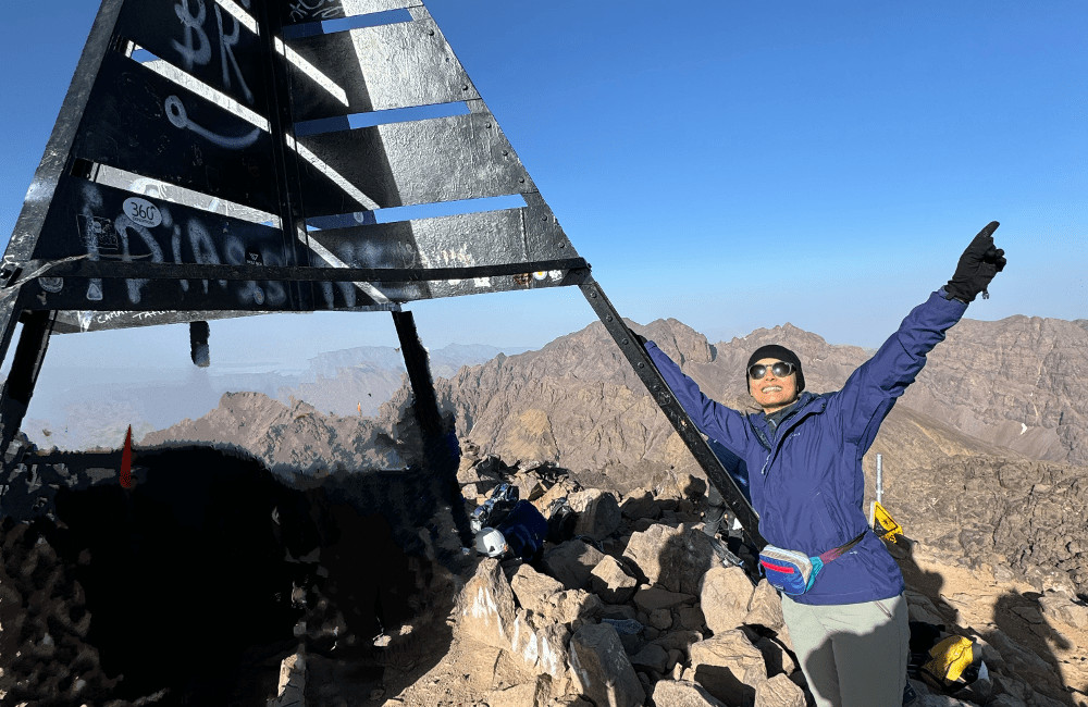 Sam on a mountain summit - Trek Training Success Story